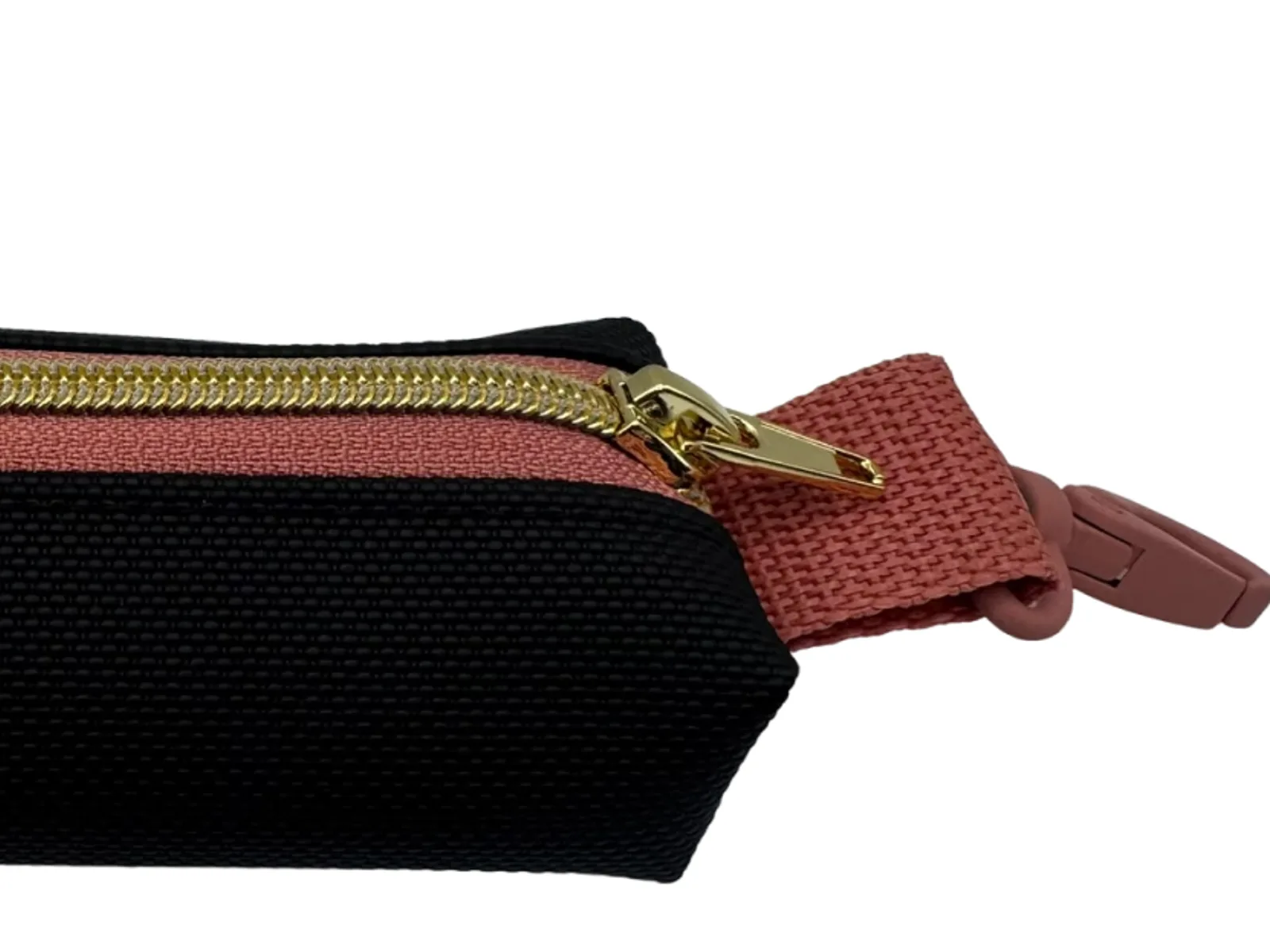 Detail: goldener Zipper und terracottafarbener Karabiner am schwarzen Täschchen